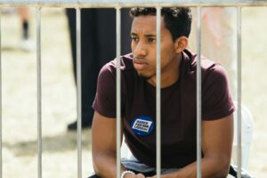 homme assis près d'une clôture métallique